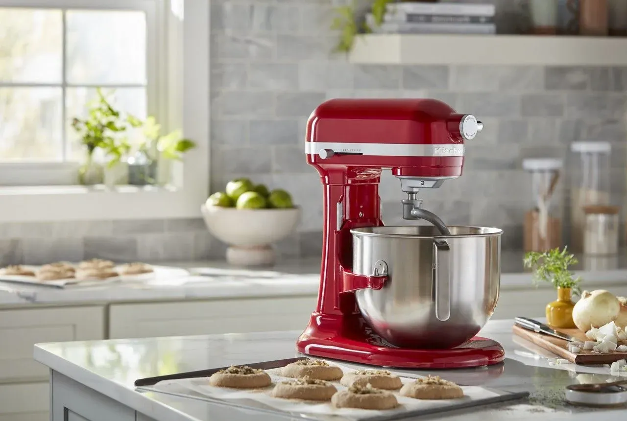 A red KitchenAid stand mixer on a kitchen counter beside a tray of fresh cookies